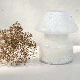 Mushroom candle lamp with white spots on clear glass. Filled with 100% soy wax with dried flowers.