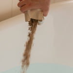 Person pouring herbal bath soak in to bath tub