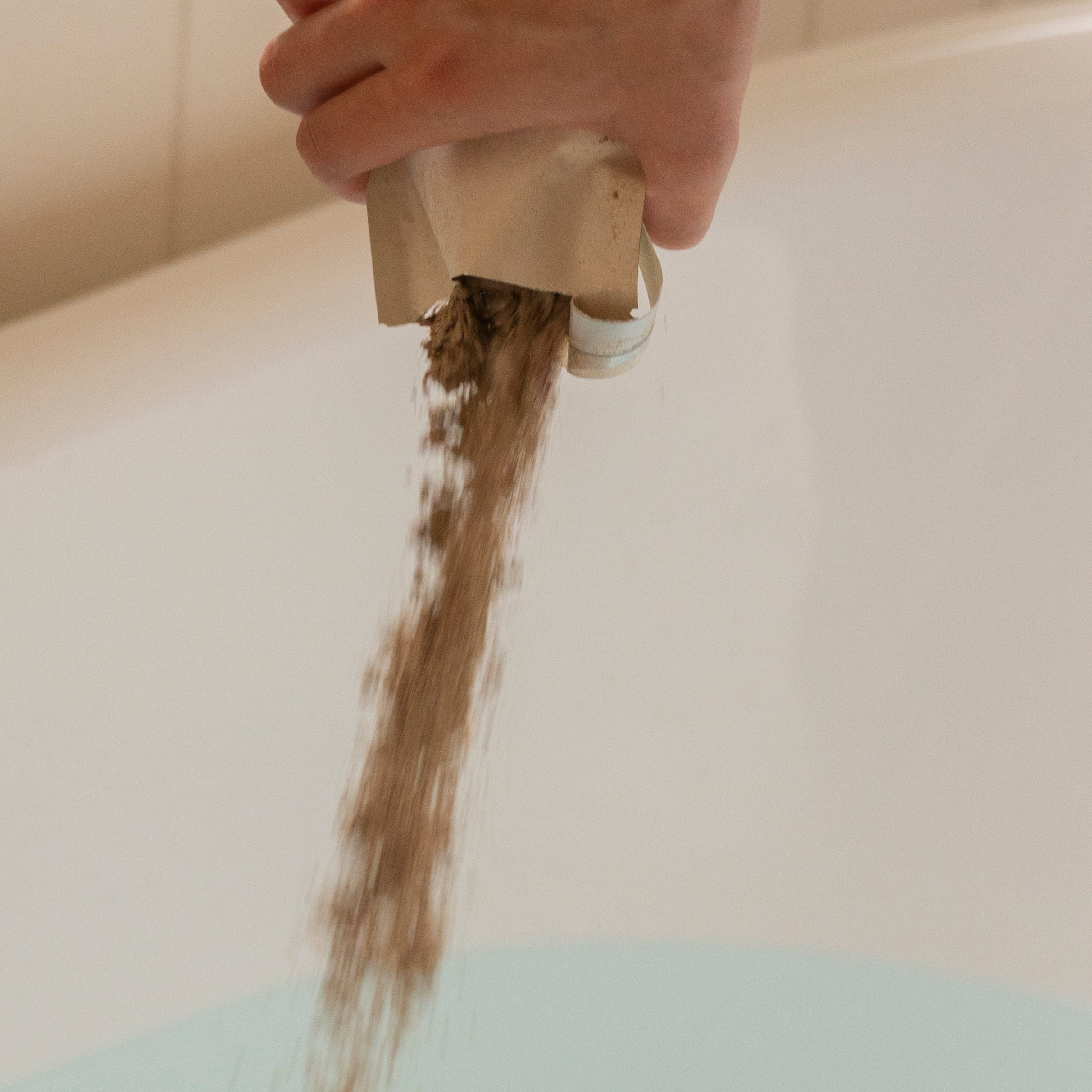 Person pouring herbal bath soak in to bath tub