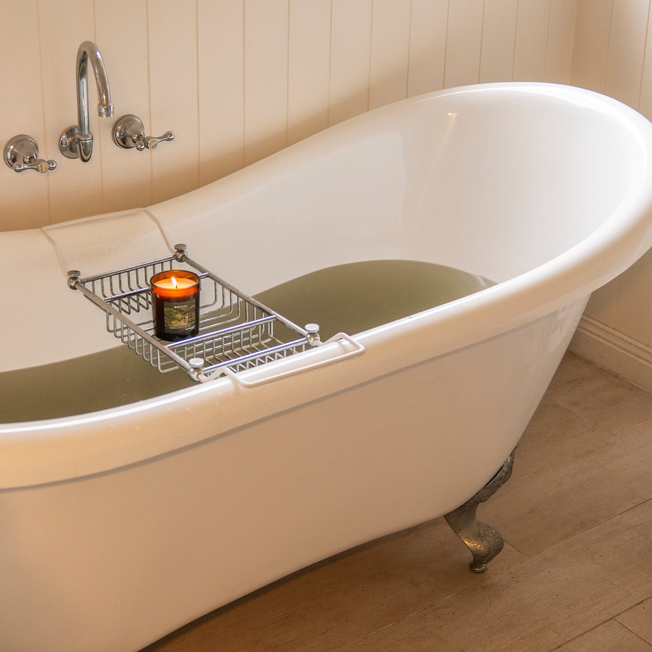White freestanding bathtub with a candle and tray in a bathroom setting. Herbal bath soak matcha and rose