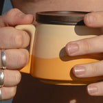 Close-up of hands holding a yellow mug with a black lid.