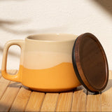 Ceramic mug with a wooden coaster on a wooden surface with a shadow of a plant.