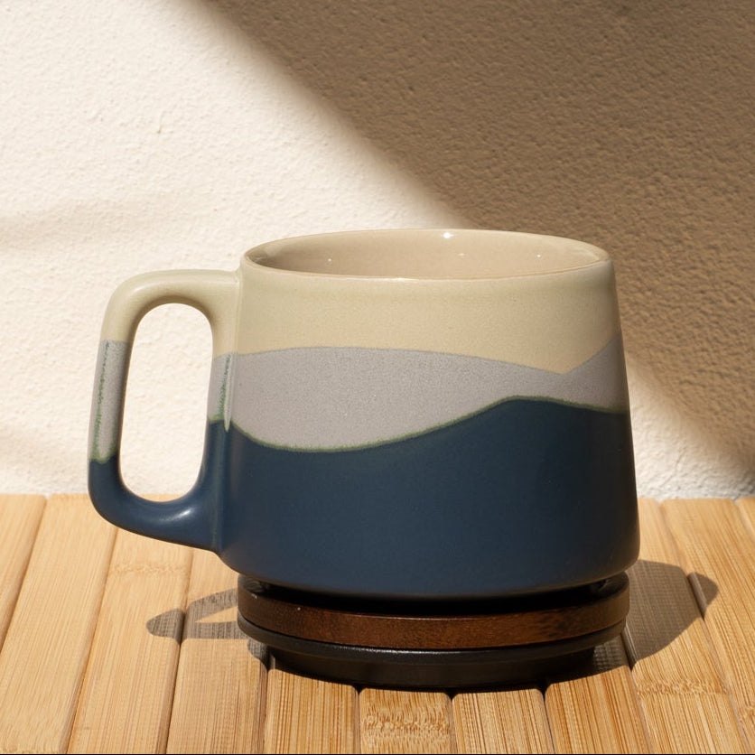Ceramic mug with blue and beige design on a wooden surface with a light background