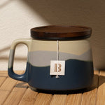 Ceramic mug with wooden lid on a wooden surface with a beige wall background