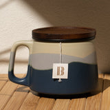 Ceramic mug with wooden lid on a wooden surface with a beige wall background