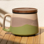 Ceramic mug with a lid on a wooden surface with a shadow of a plant.