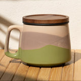 Ceramic mug with a lid on a wooden surface with a shadow of a plant.
