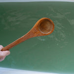 Wooden ladle held by a hand herbal bath water
