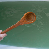 Wooden ladle held by a hand herbal bath water