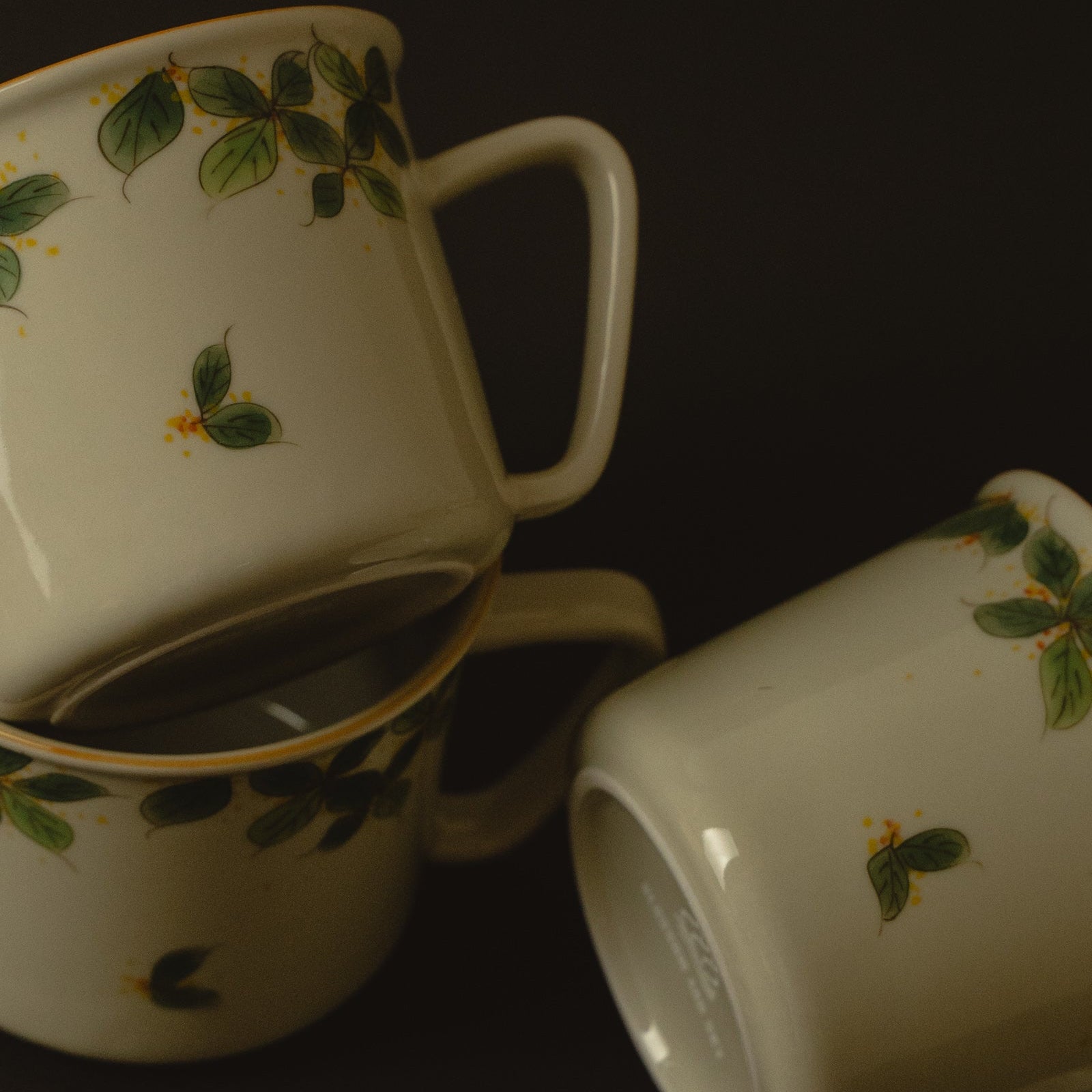 Two ceramic mugs with leaf patterns on a dark background