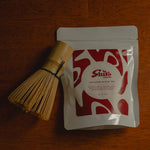 Tea packaging with a whisk on a wooden surface