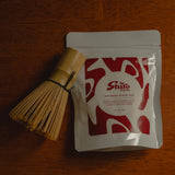 Tea packaging with a whisk on a wooden surface