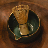 Traditional Japanese tea whisk (chasen) in a ceramic bowl on a wooden surface