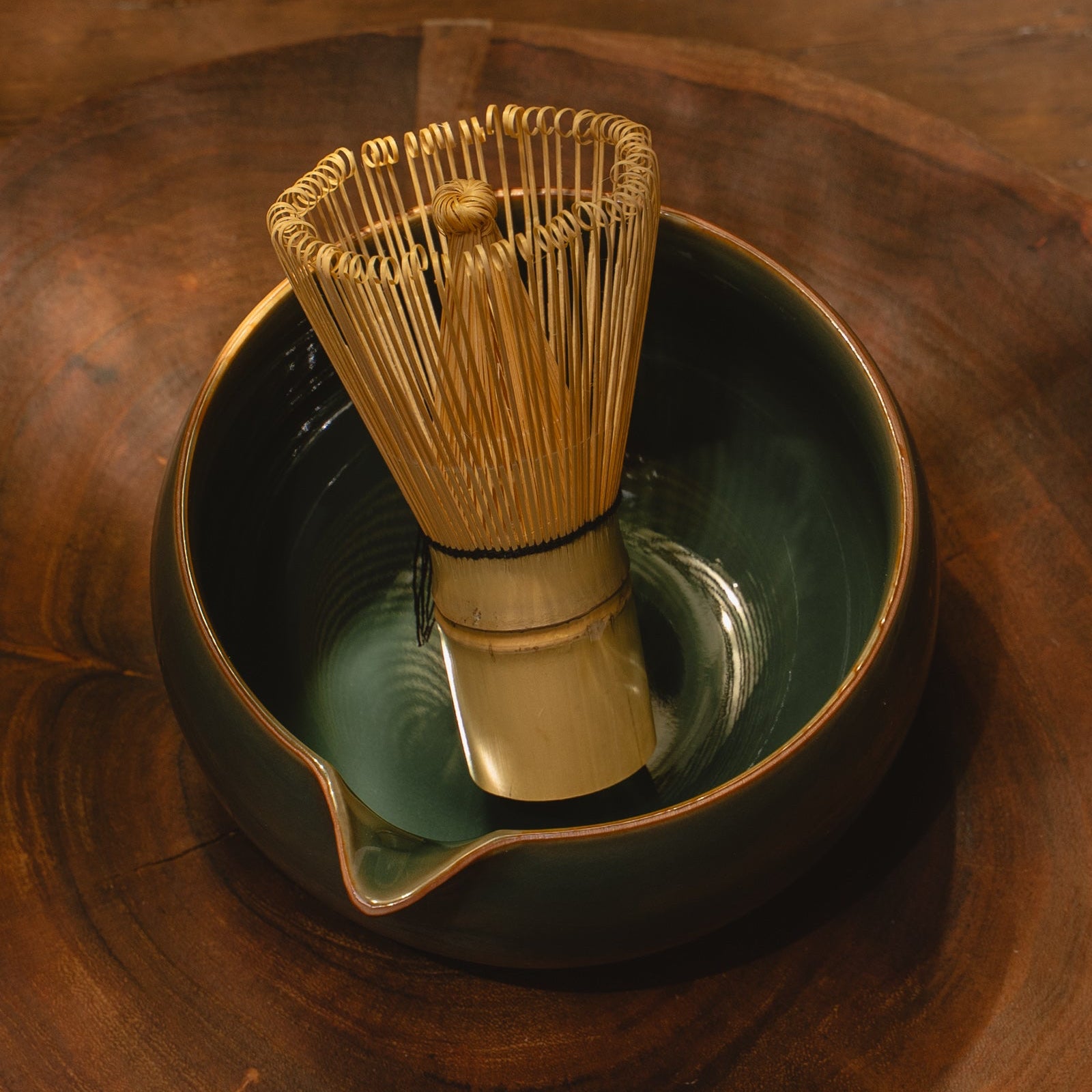 Traditional Japanese tea whisk (chasen) in a ceramic bowl on a wooden surface