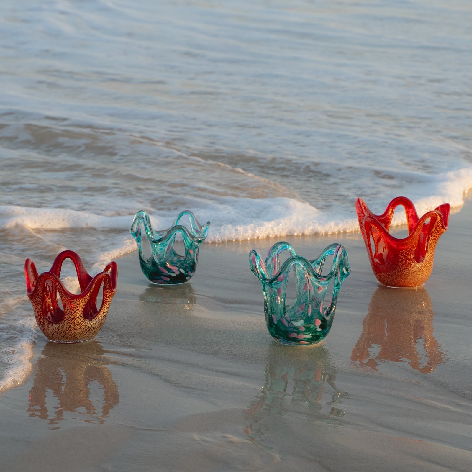 Colorful glass bowls on a beach with ocean waves in the background