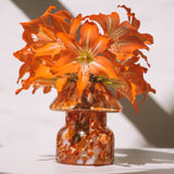 Mushroom candle lamp with red, orange and white spots on clear glass. Retro lamp is filled flowers being used as a vase.