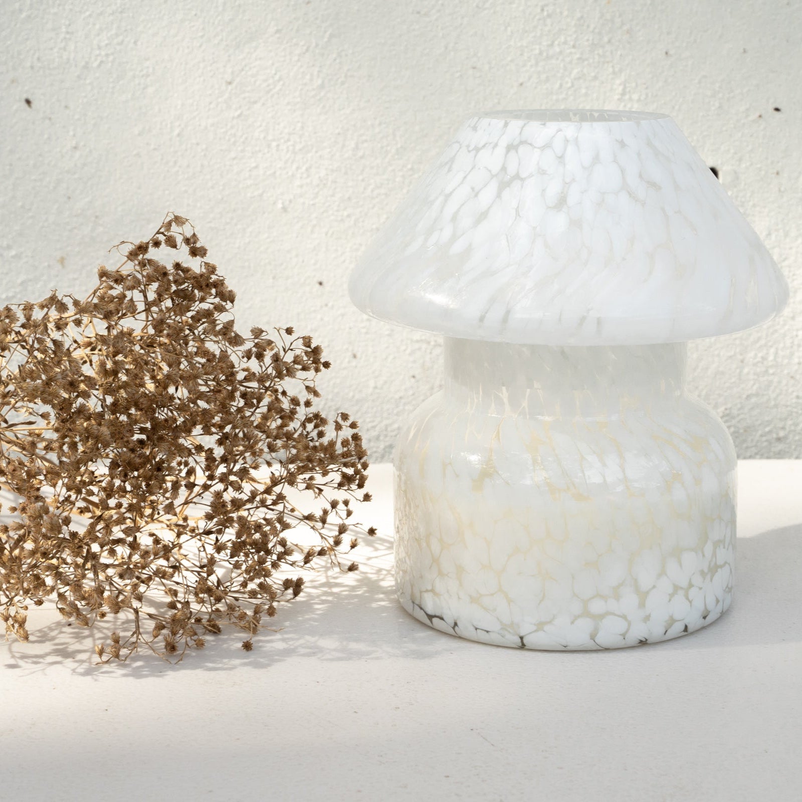 Mushroom candle lamp with white spots on clear glass. Filled with 100% soy wax with dried flowers.