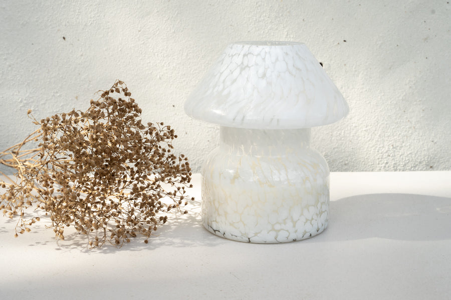 Mushroom candle lamp with white spots on clear glass. Filled with 100% soy wax with dried flowers.