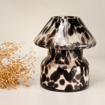 Mushroom candle lamp with black spots on clear glass. Filled with 100% soy wax with dried flowers.