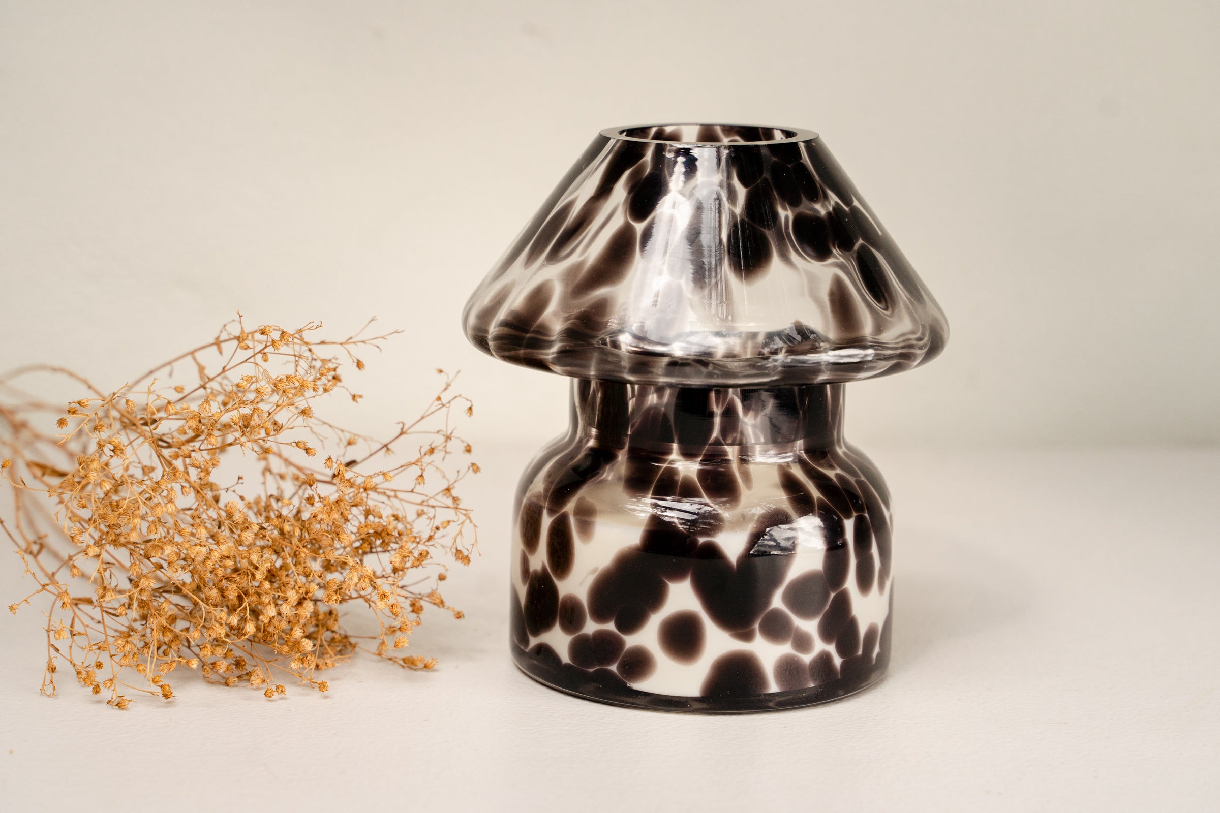Mushroom candle lamp with black spots on clear glass. Filled with 100% soy wax with dried flowers.