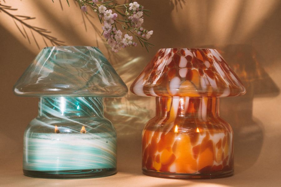 Mushroom candle lamp with aqua blue and gold glitter swirls on clear glass. Mushroom lamp is placed next to retro candle lamp.